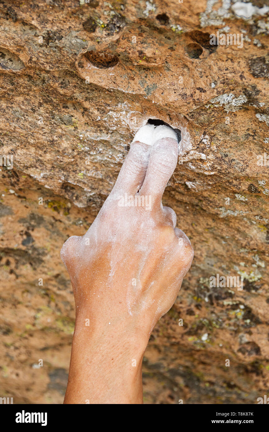 womans hand grabbing a bad two finger pocket on a steep tuff rock climb Stock Photo