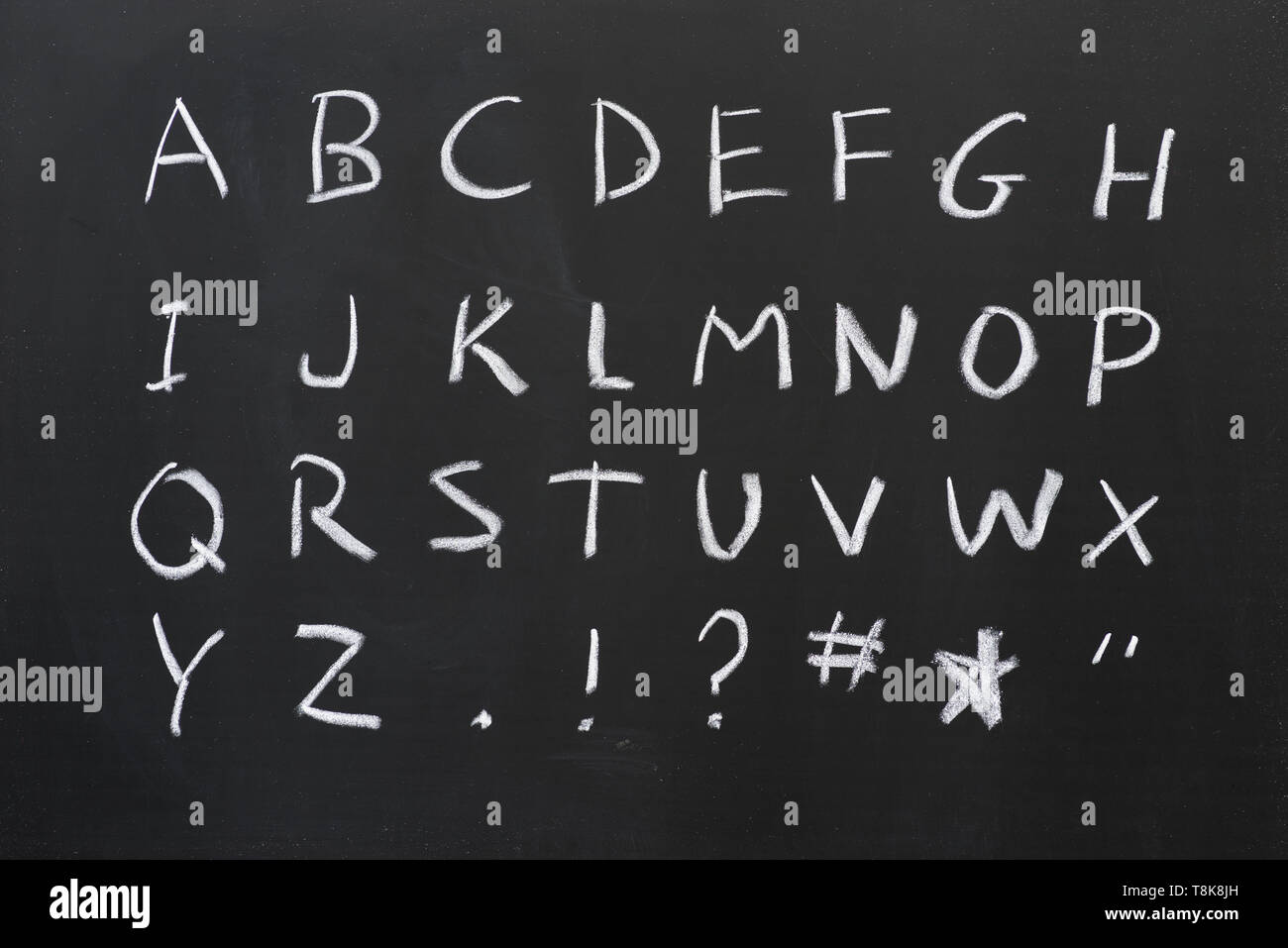 capital alphabet written in white chalk on a blackboard with some symbols Stock Photo