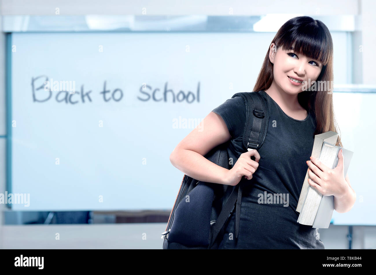 Asian student woman with backpack carrying book in the classroom with ...