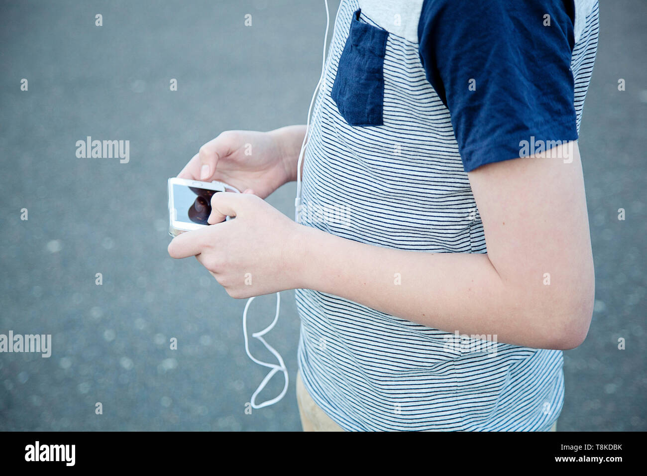 Boy walking on road while using smart phone Stock Photo