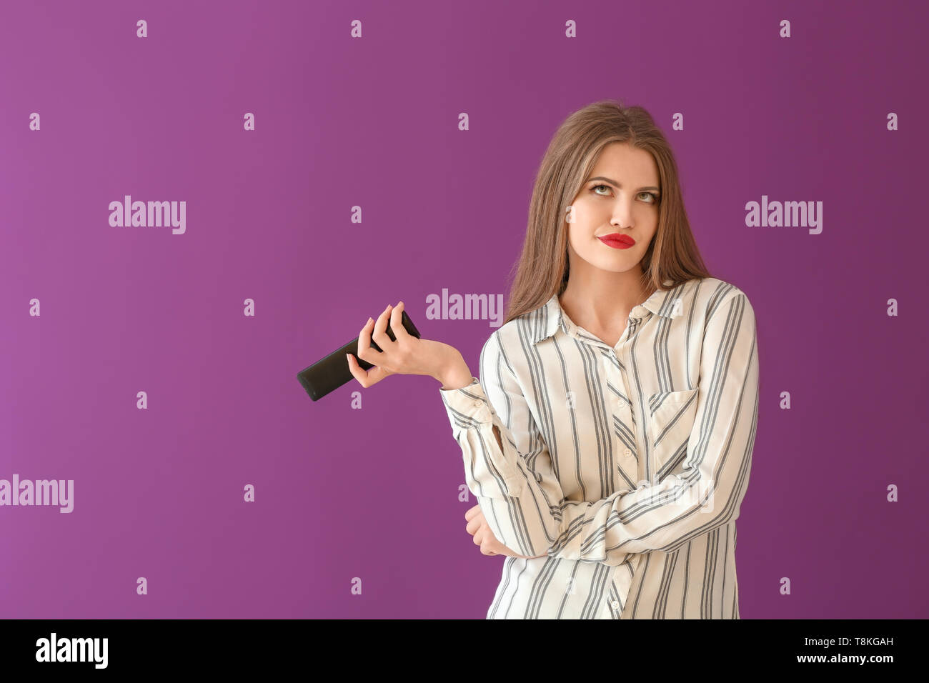 Emotional young woman with remote control on color background Stock ...