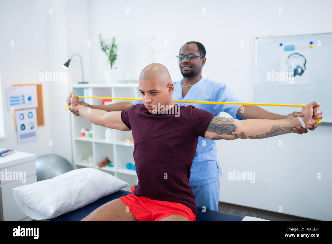 Bodybuilder stretching his arms while having physical therapy Stock