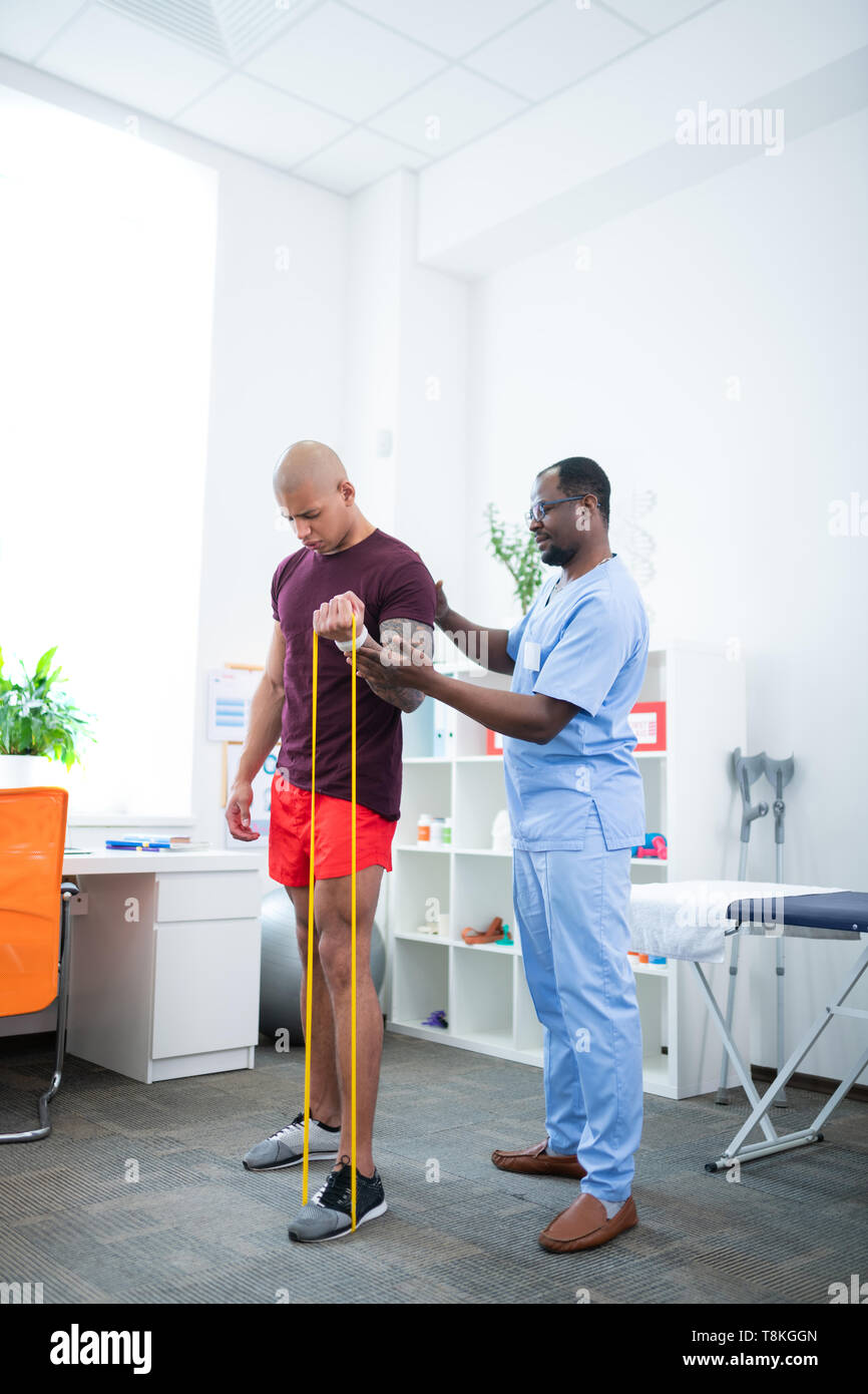 Bodybuilder flexing his muscles while visiting sports therapist Stock