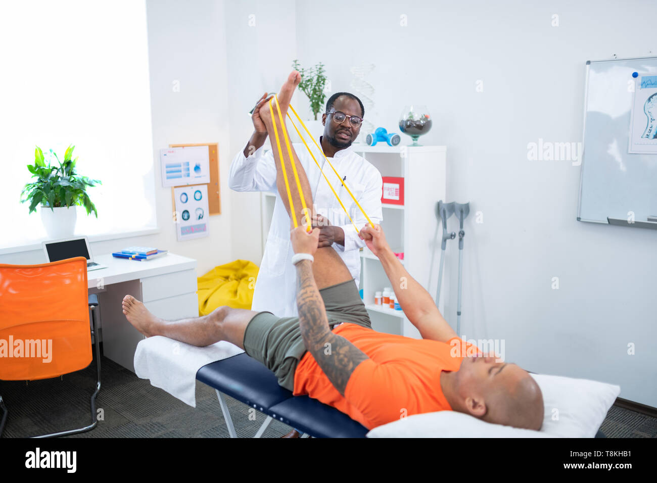 Man holding yellow ribbon while stretching leg visiting therapist Stock Photo