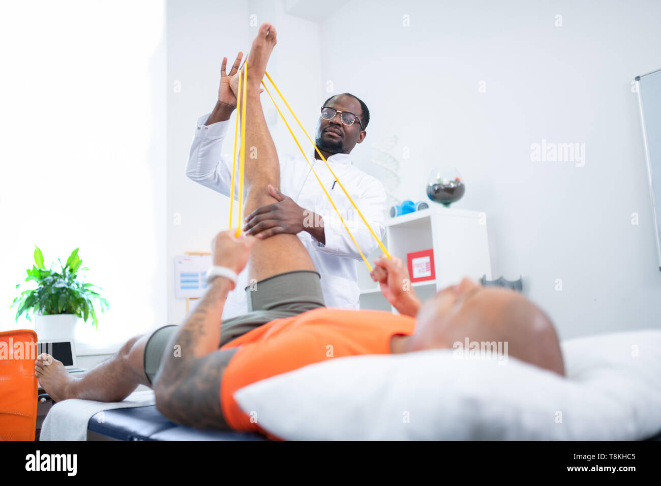 Therapist helping his patient stretching leg after training Stock Photo