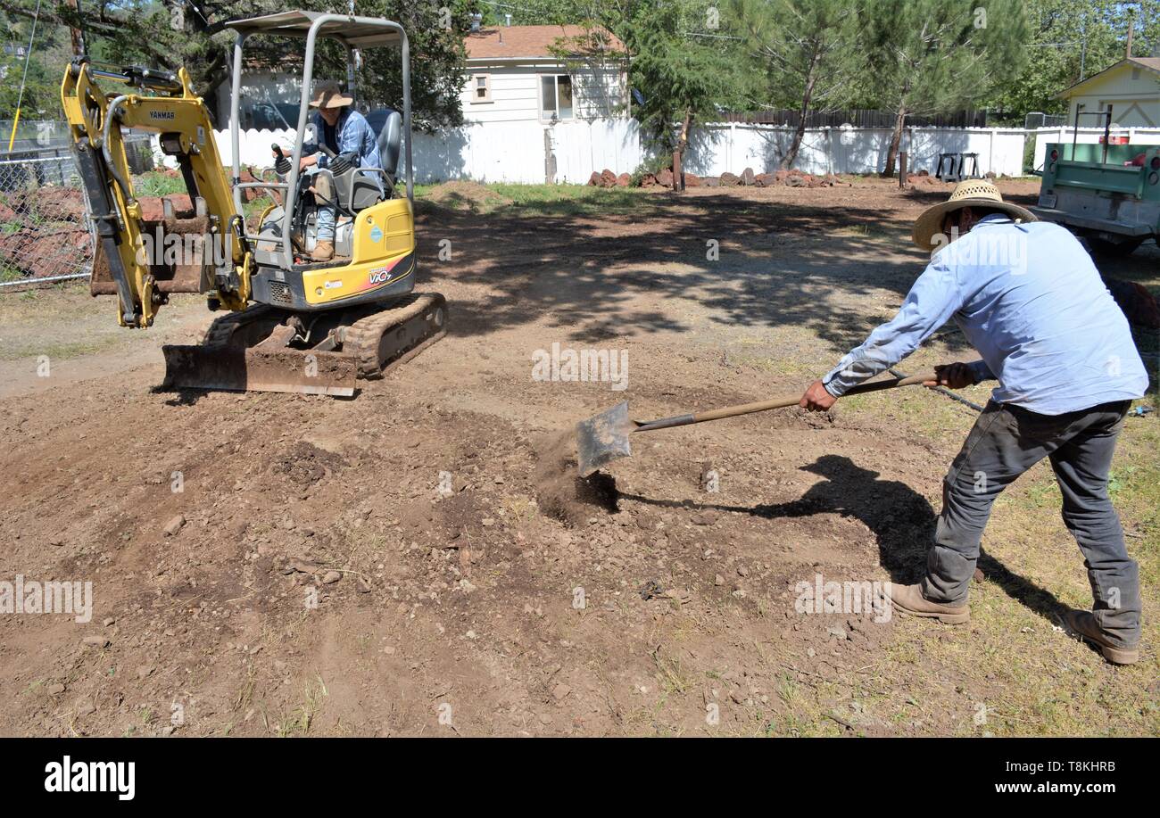 Moving rocks and installing piping for landscaping, by Mexican laborers 