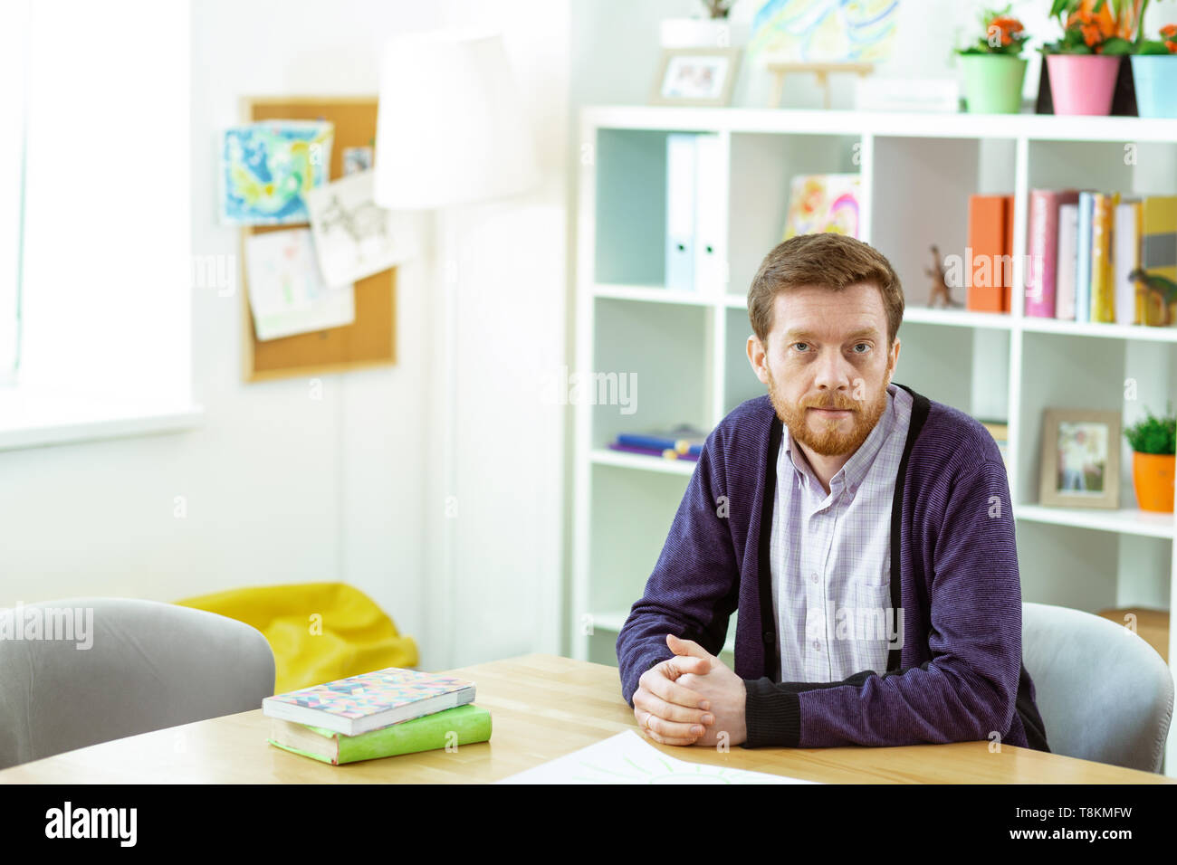 Calm bearded man sitting in a classroom and waiting for his students Stock Photo