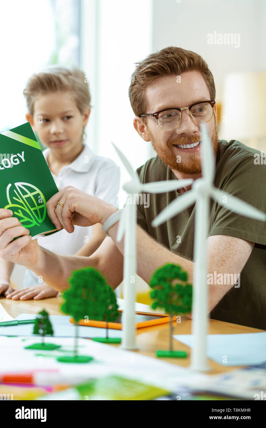 Contented ginger teacher in clear glasses spending time with little