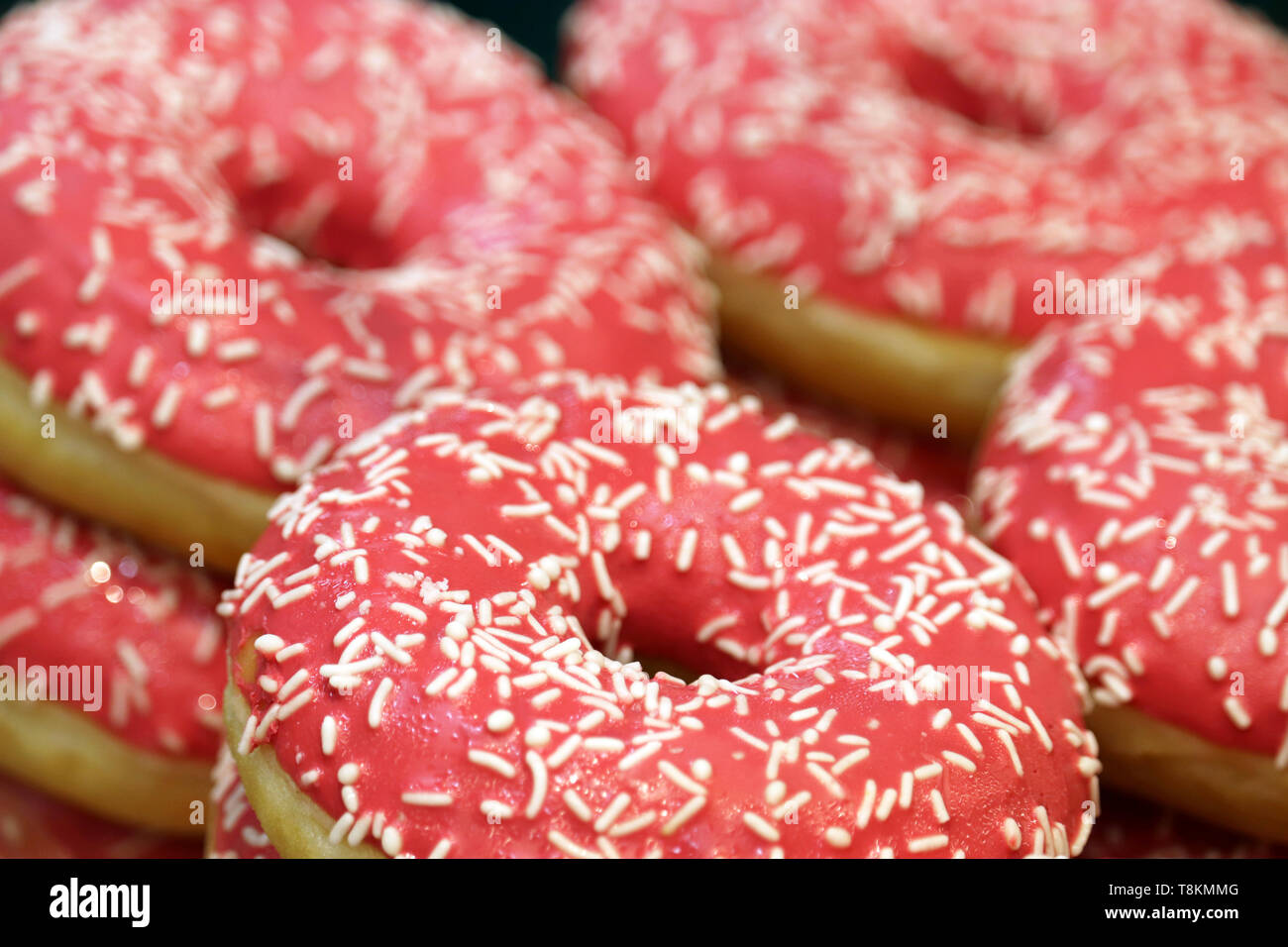 Doughnuts in pink glaze with sprinkles close up. Colorful sweet donuts for background Stock Photo