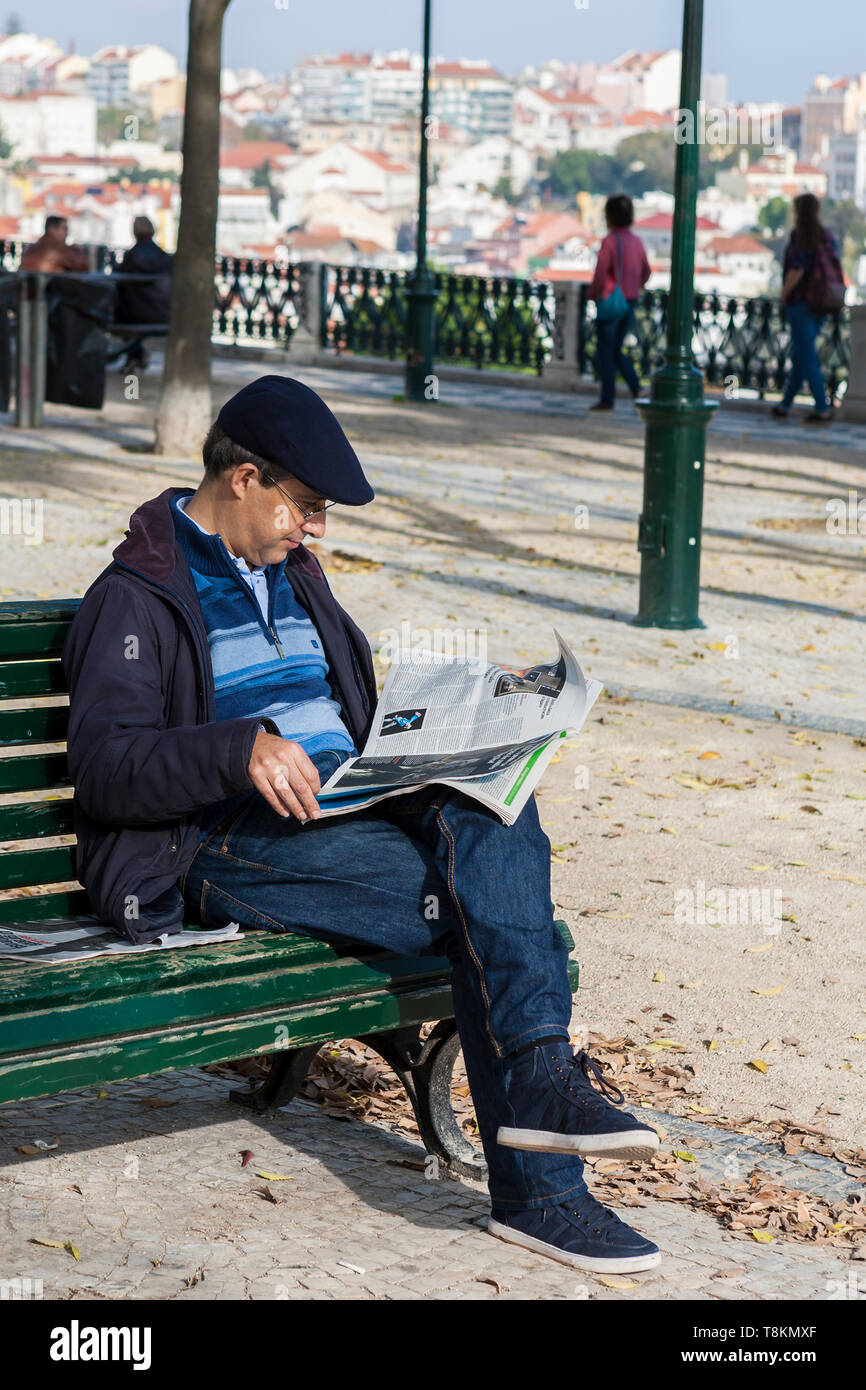 Jardim de São Pedro de Alcântara, Lisbon, Portugal: a man sits on a park bench to read the newspaper Stock Photo