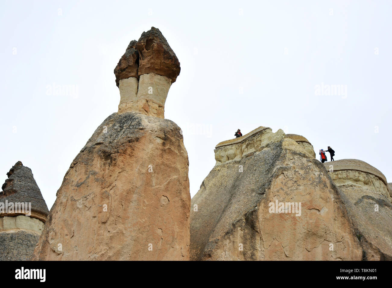 Visitors climb on strange rock formations at Cappadocia, Turkey Stock Photo
