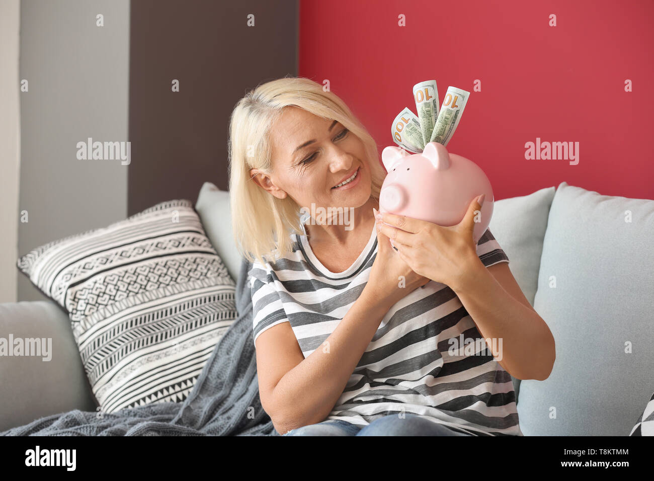 Mature woman with piggy bank at home Stock Photo - Alamy