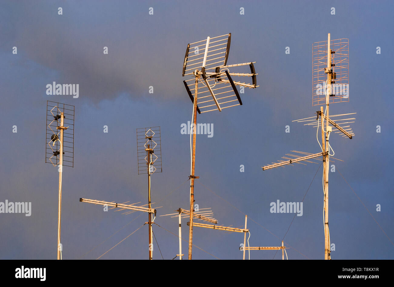 Different kinds of TV antennas and arrays against a cloudy sky Stock Photo