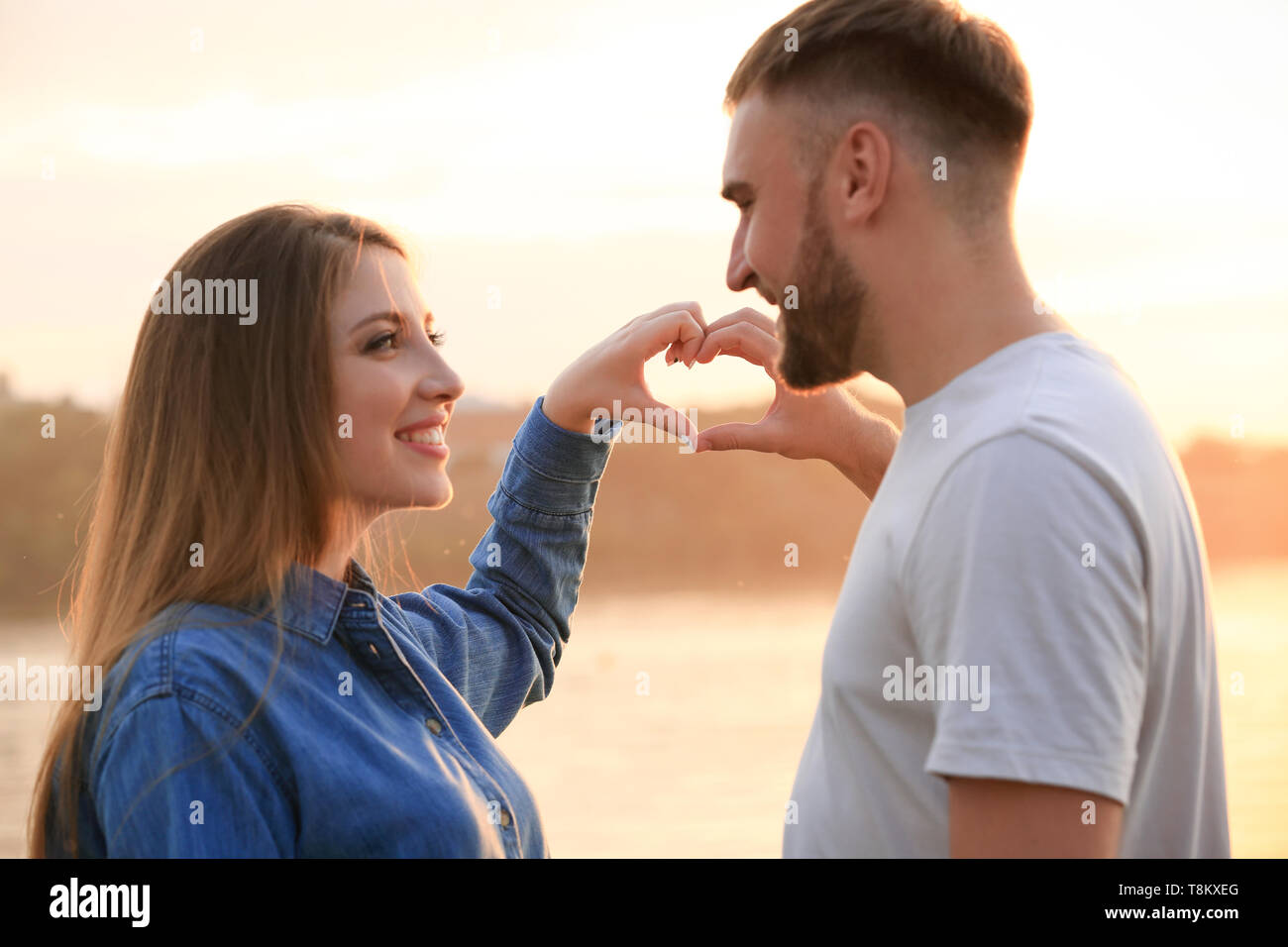 Happy couple making heart with their hands near river Stock Photo - Alamy