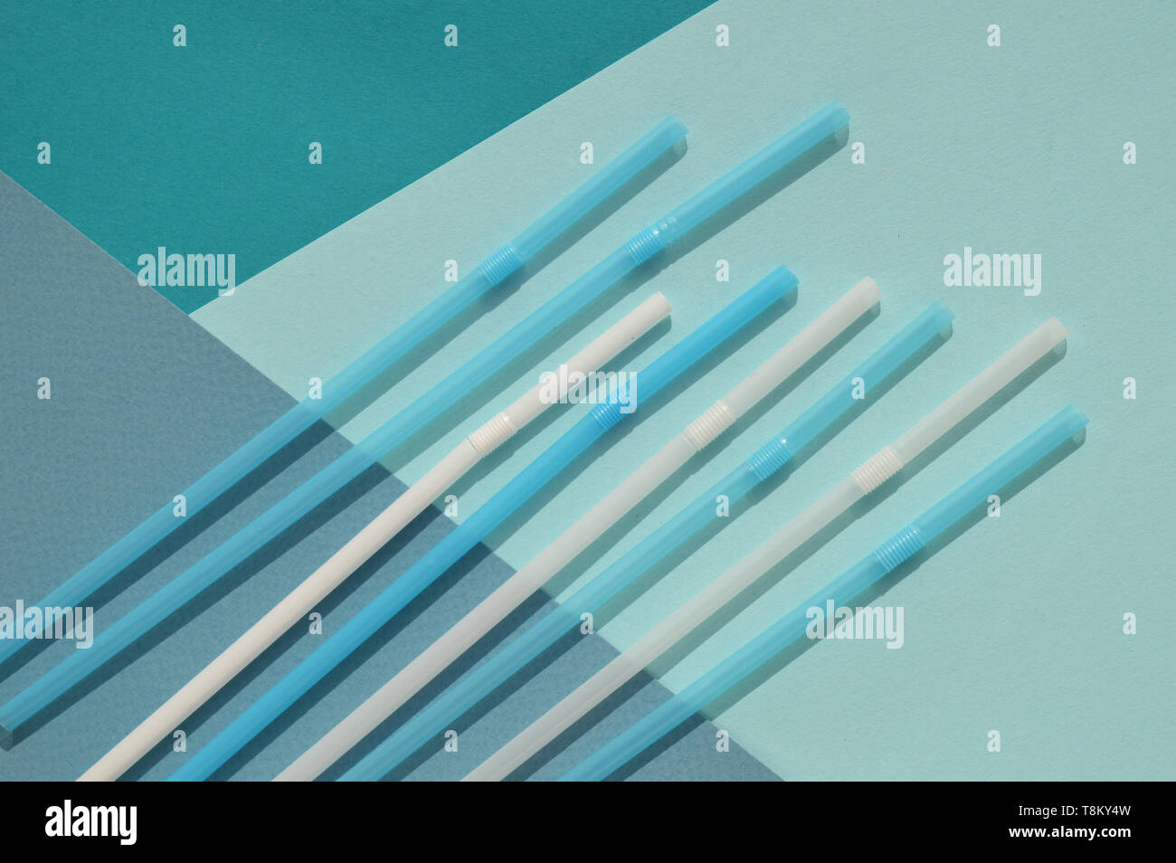 Turquoise and white plastic tubules on a mixed background of different tones of blue color. Plastic concept. Stock Photo
