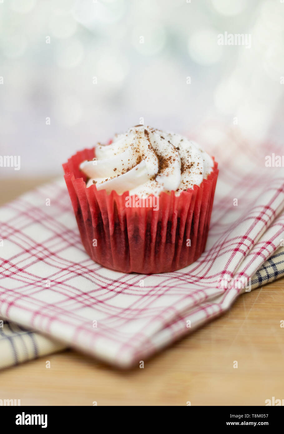 Red velvet cupcake on decorative plaid cloth with a shallow depth of field and a bokeh background Stock Photo