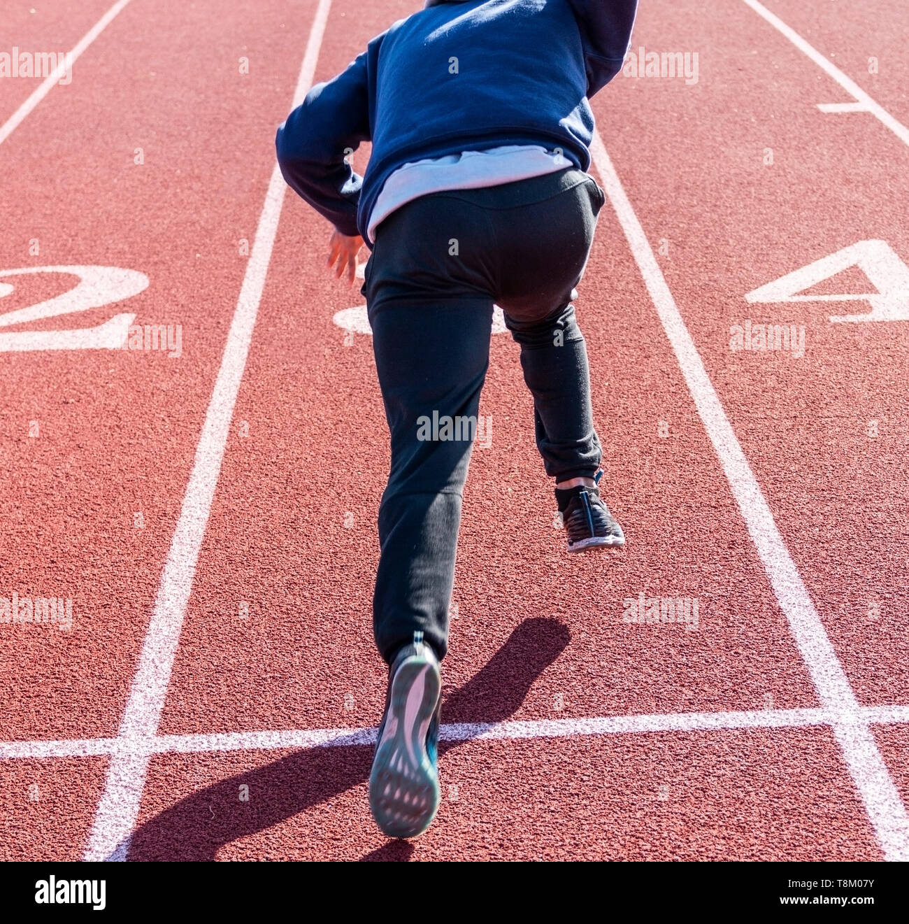 A high school sprinter is practicing his running starts on a track at
