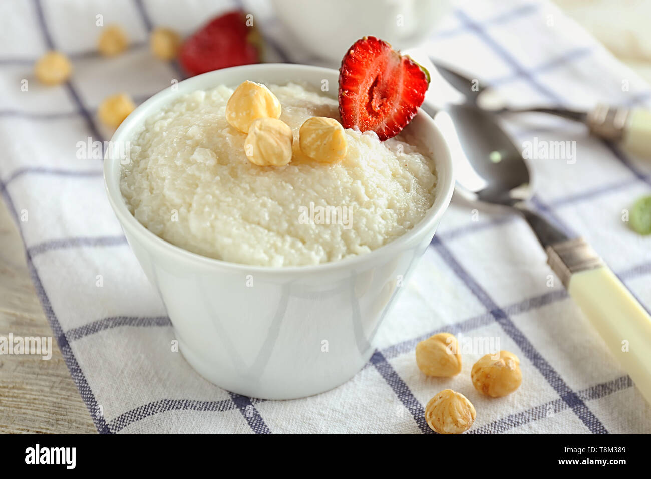 Delicious rice pudding with strawberry and hazelnuts in bowl on table Stock Photo