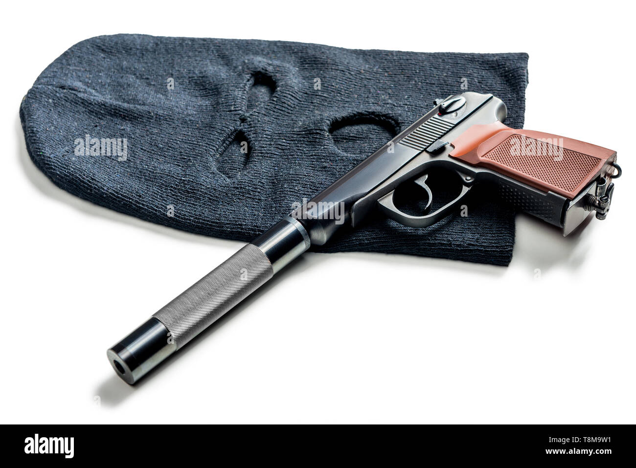 black balaclava and a pistol with a silencer close up on a white table Stock Photo