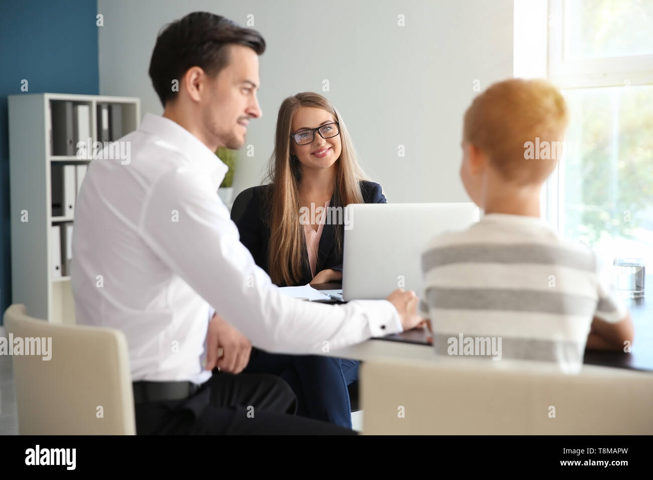 Young man and his son meeting with headmistress at school Stock Photo