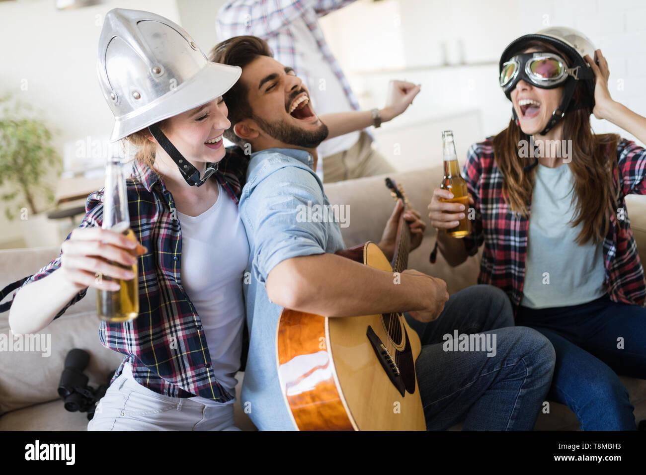 Group of friends playing guitar and partying at home Stock Photo