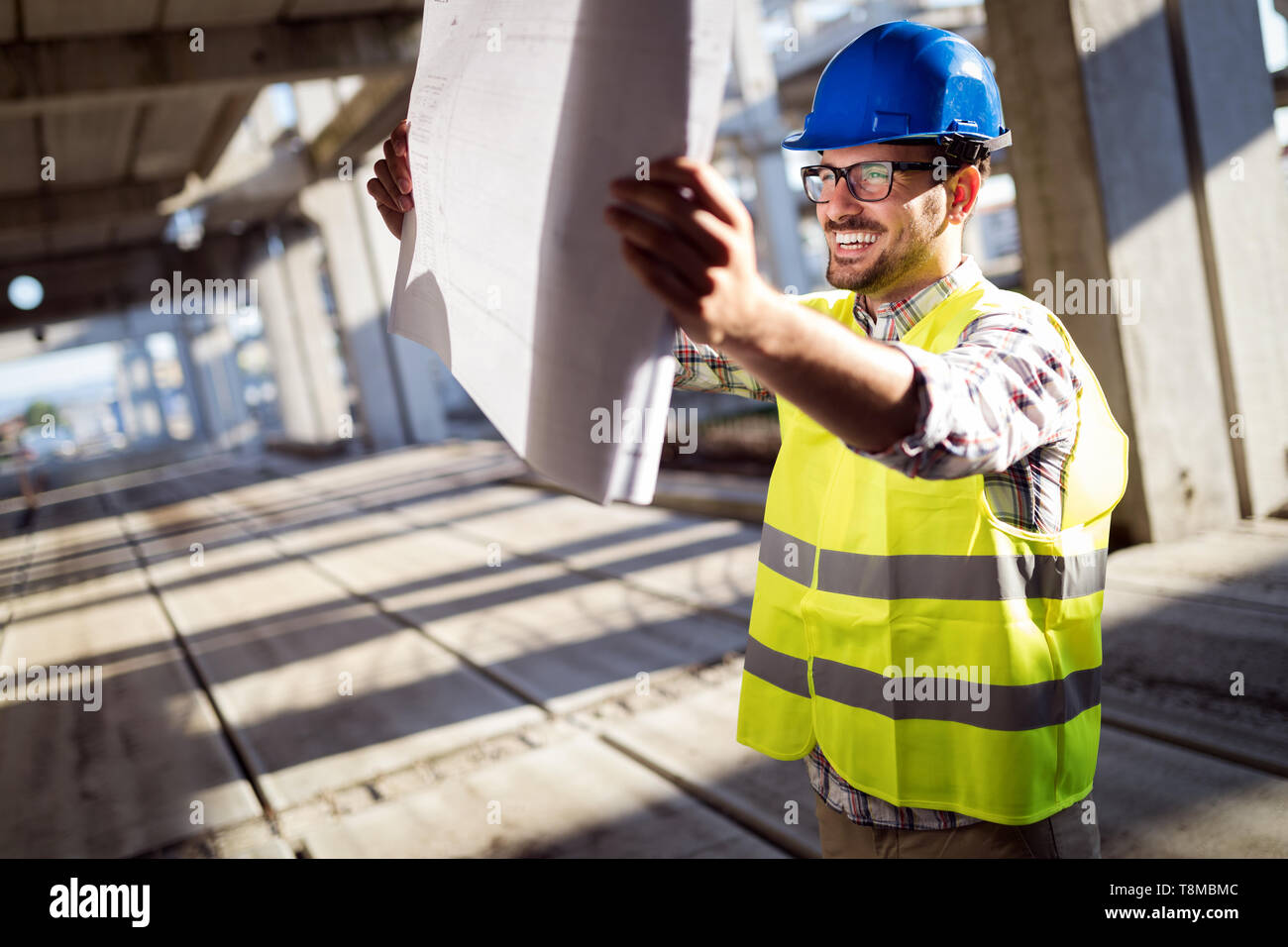 Engineer working on construction site and holding blueprint Stock Photo ...