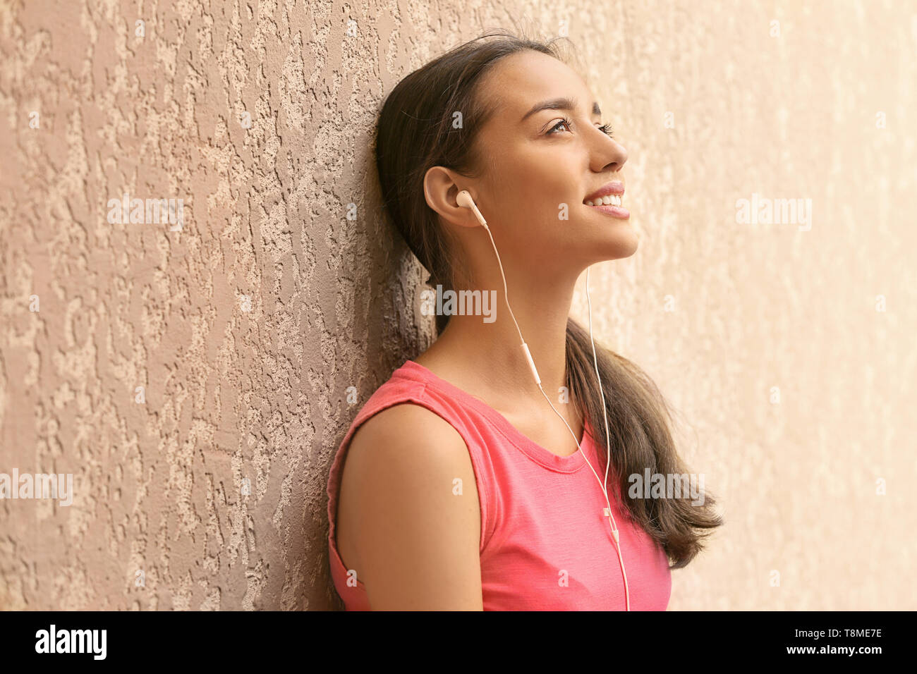 Beautiful young woman listening to music near color wall Stock Photo ...