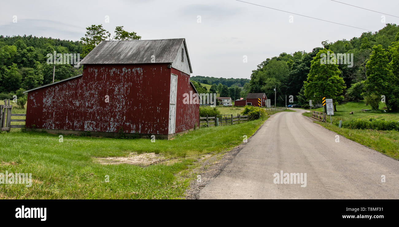 Claysville, Pennsylvania/USA- June 8, 2018:  Faded red barn on a country road in rural Appalachia. Stock Photo