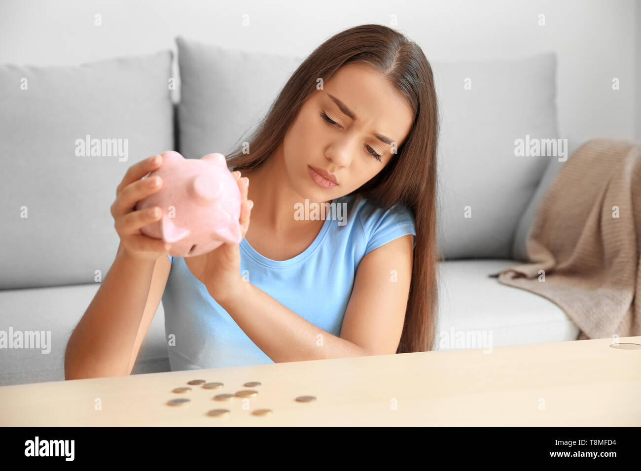 Sad young woman with empty piggy bank at home Stock Photo - Alamy