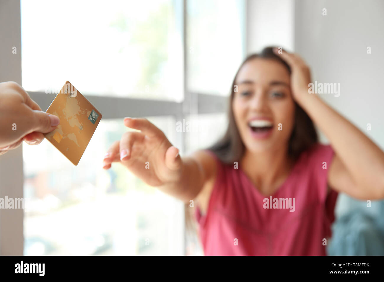 Happy young woman stretching hand for credit card Stock Photo