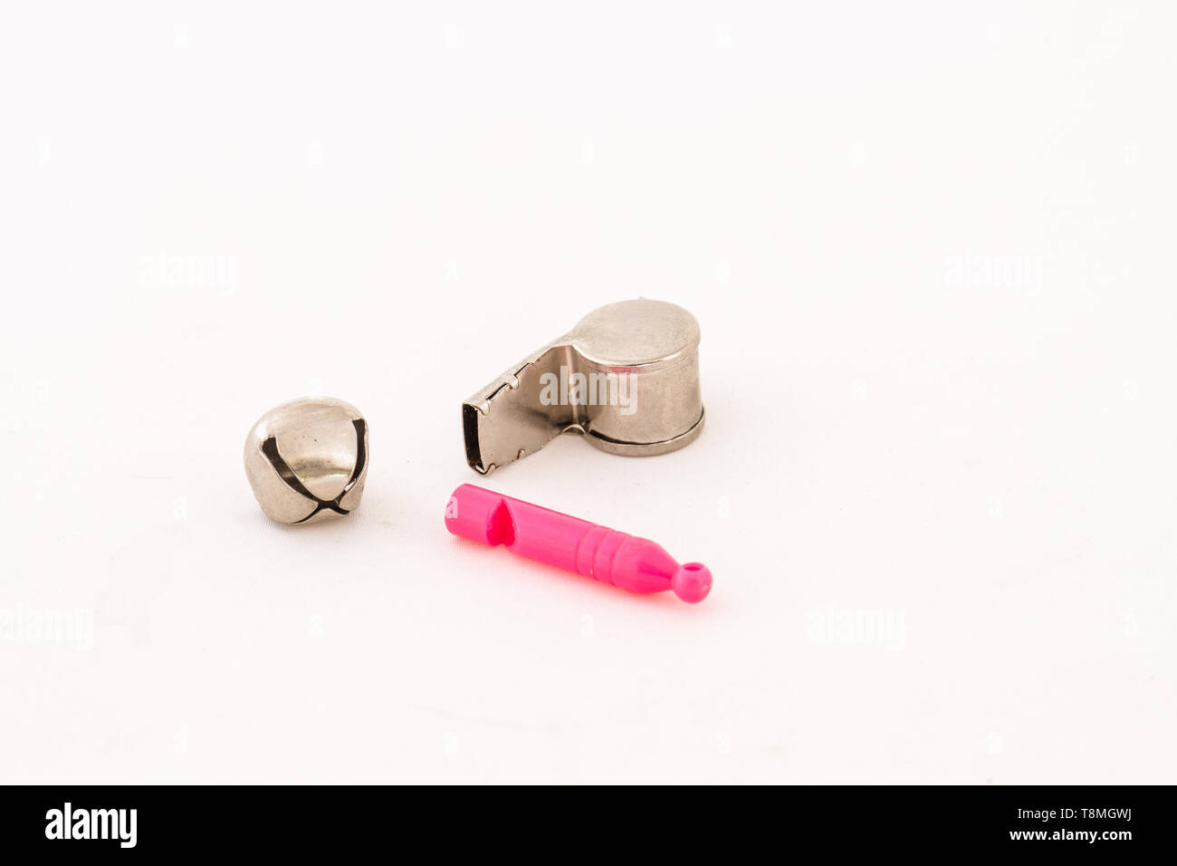 Two whistles and a silver bell isolated on a white background image with copy space in landscape format Stock Photo