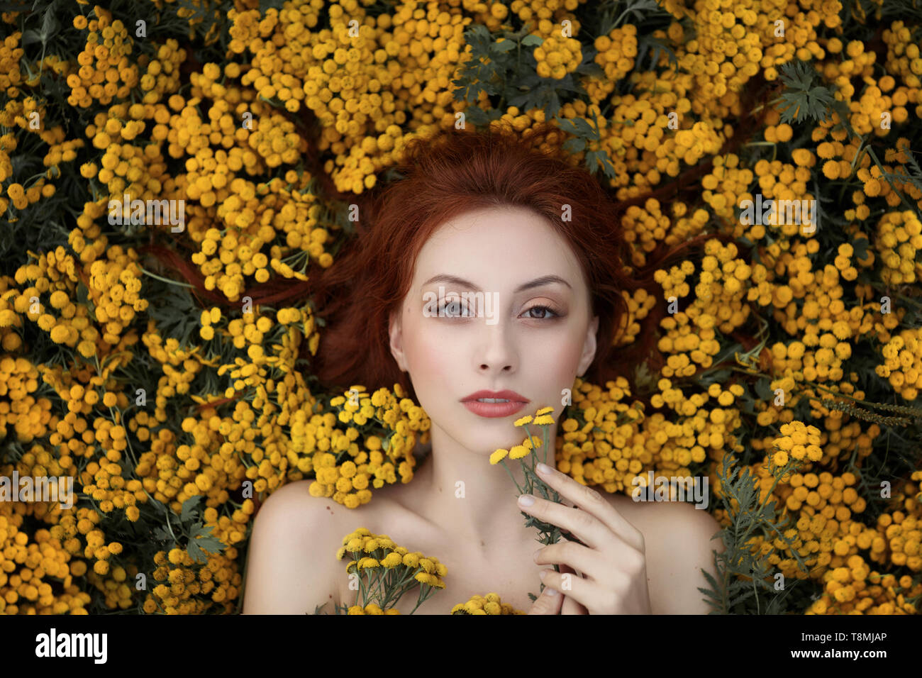 Portrait of a girl lying in flowers Stock Photo - Alamy