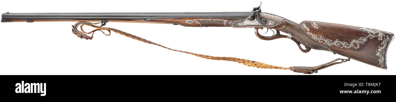 A double-barrelled percussion shotgun, Blasius Sailer in Ehingen, circa 1820 Smooth two-stage barrels in 15.5 mm calibre, octagonal then round, the front half attached. The midrib with silver-inlaid tendrils, the tops of the barrels with motto (tr.) 'I am a hunter, in the distance I stand and I like shooting foxes and birds'. Converted percussion locks. Half stock with typical, lavish silver inlays (some are missing) and finely engraved, iron furniture. Later wooden ramrod with horn tip. Traces of age and use, the stock with cracks and repairs. L, Additional-Rights-Clearance-Info-Not-Available Stock Photo
