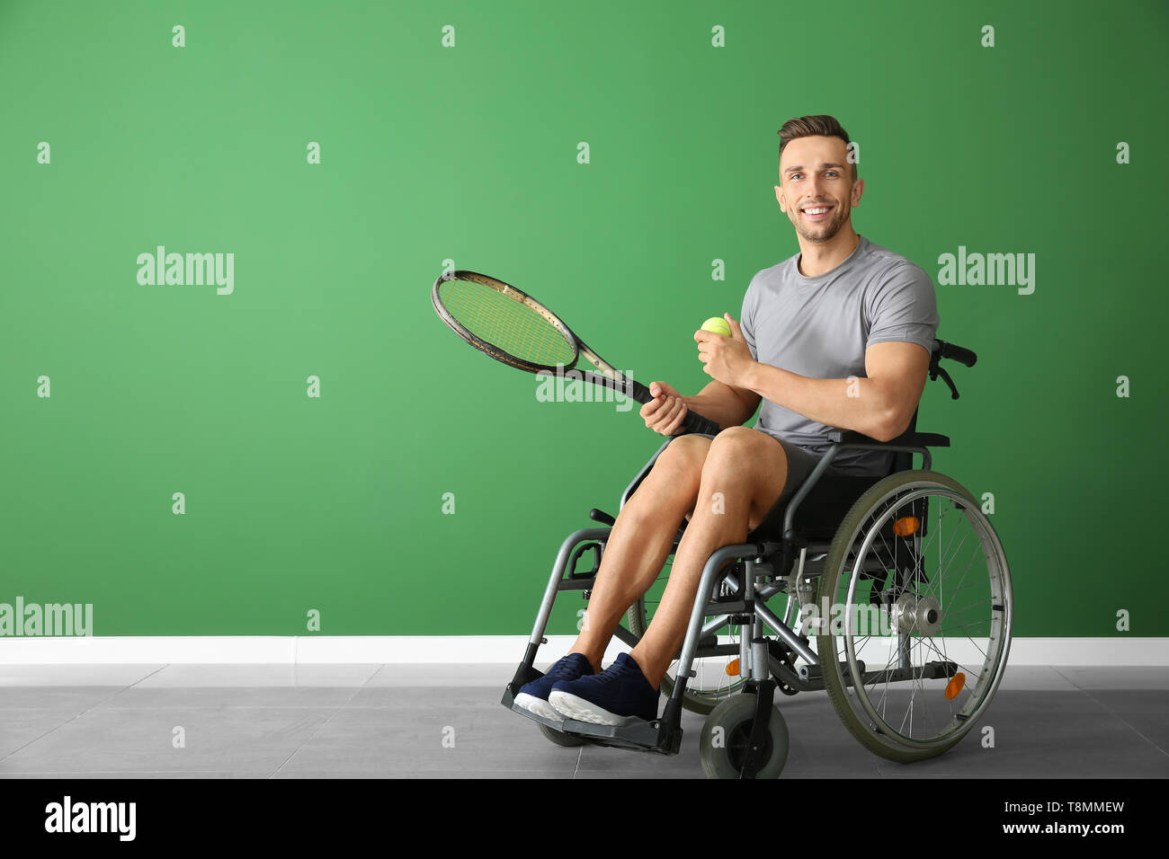 Man Using Tennis Racket Sporty young man with tennis racket and ball sitting in wheelchair ...