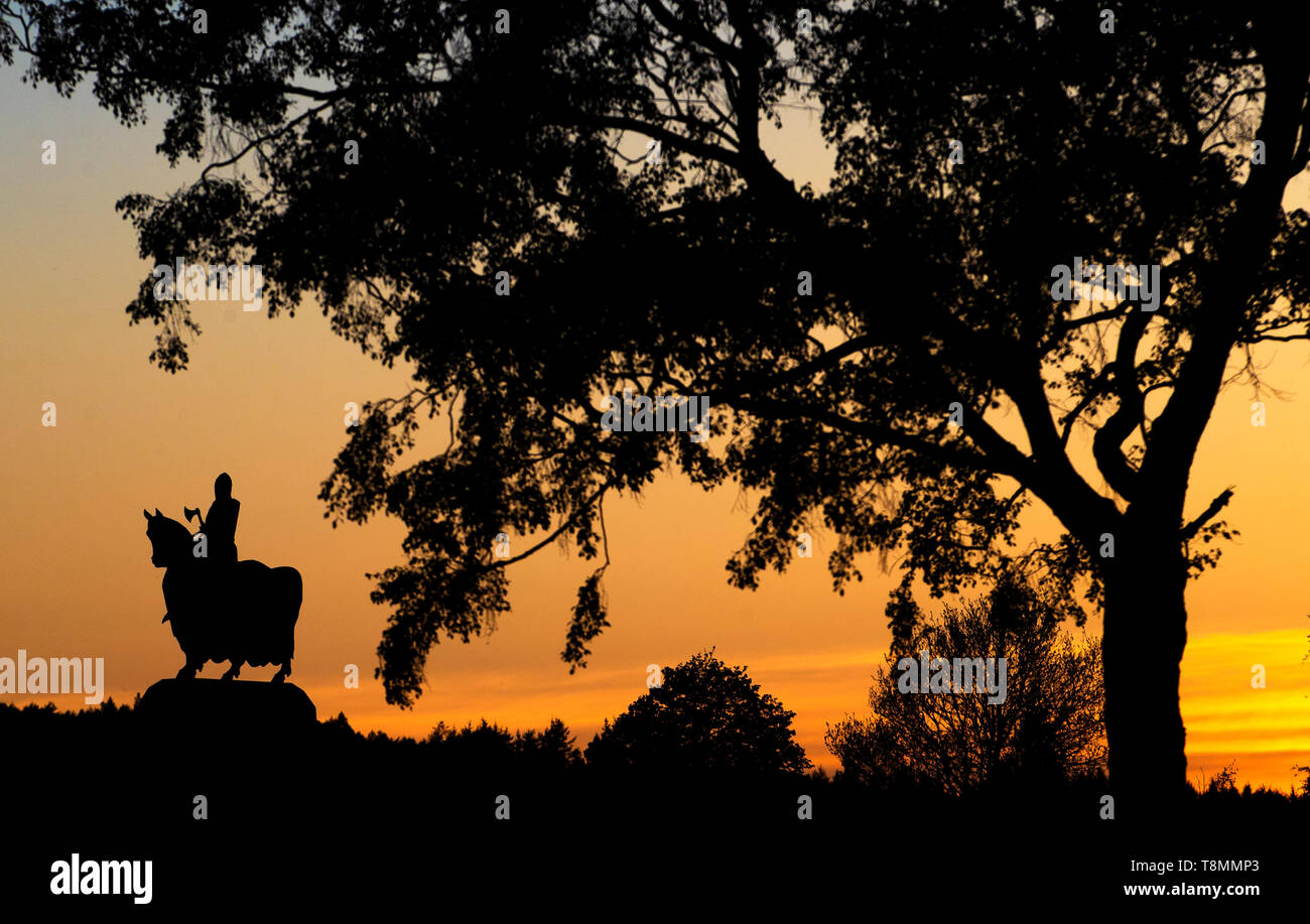 The sun sets behind the statue of Robert the Bruce on his war horse at the Battle of Bannockburn site near Stirling. Stock Photo
