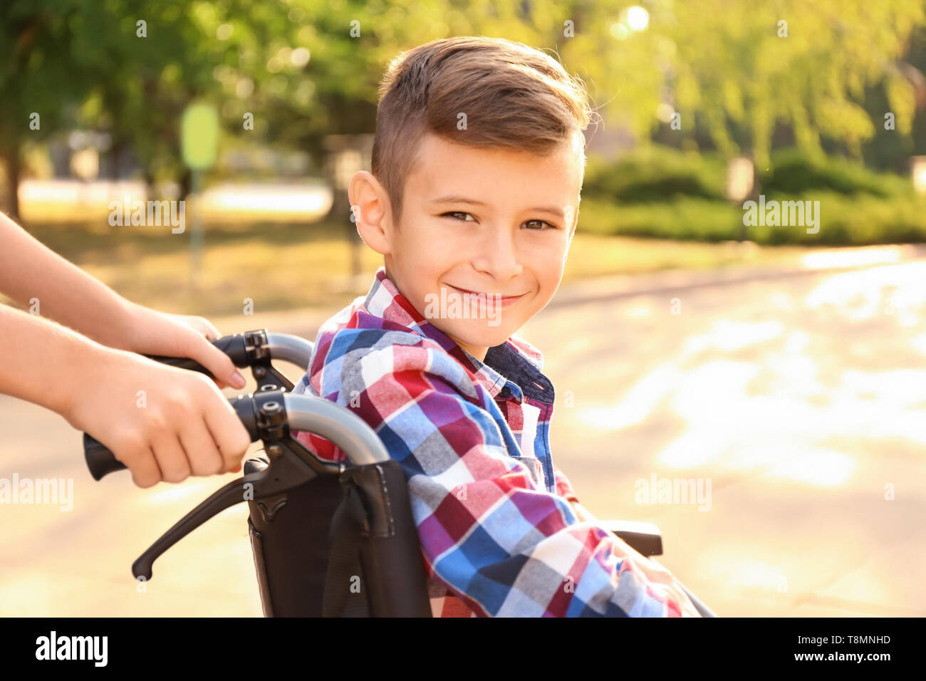 Boy in wheelchair and his sister outdoors Stock Photo