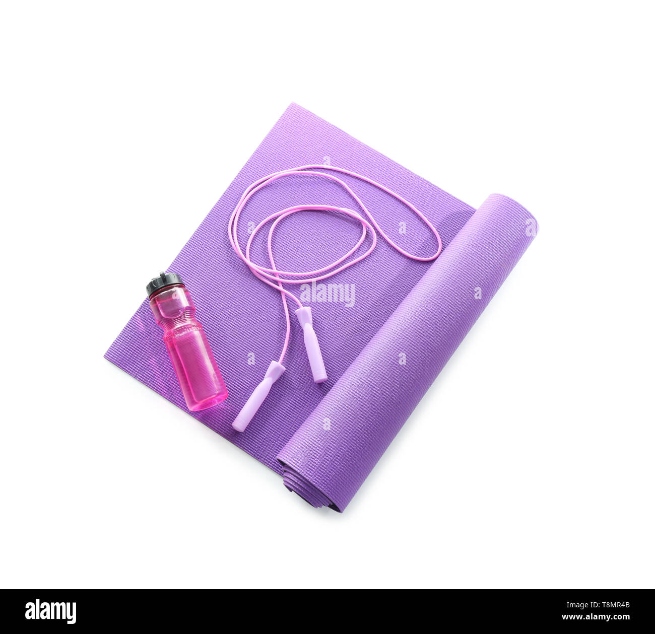 Yoga mat with jumping rope and bottle of water on white background