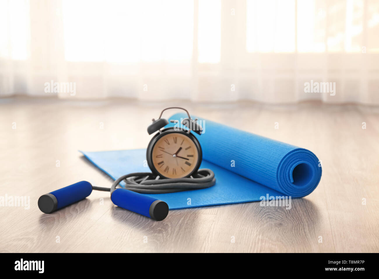 Yoga Mat With Jumping Rope And Alarm Clock On Floor Stock Photo
