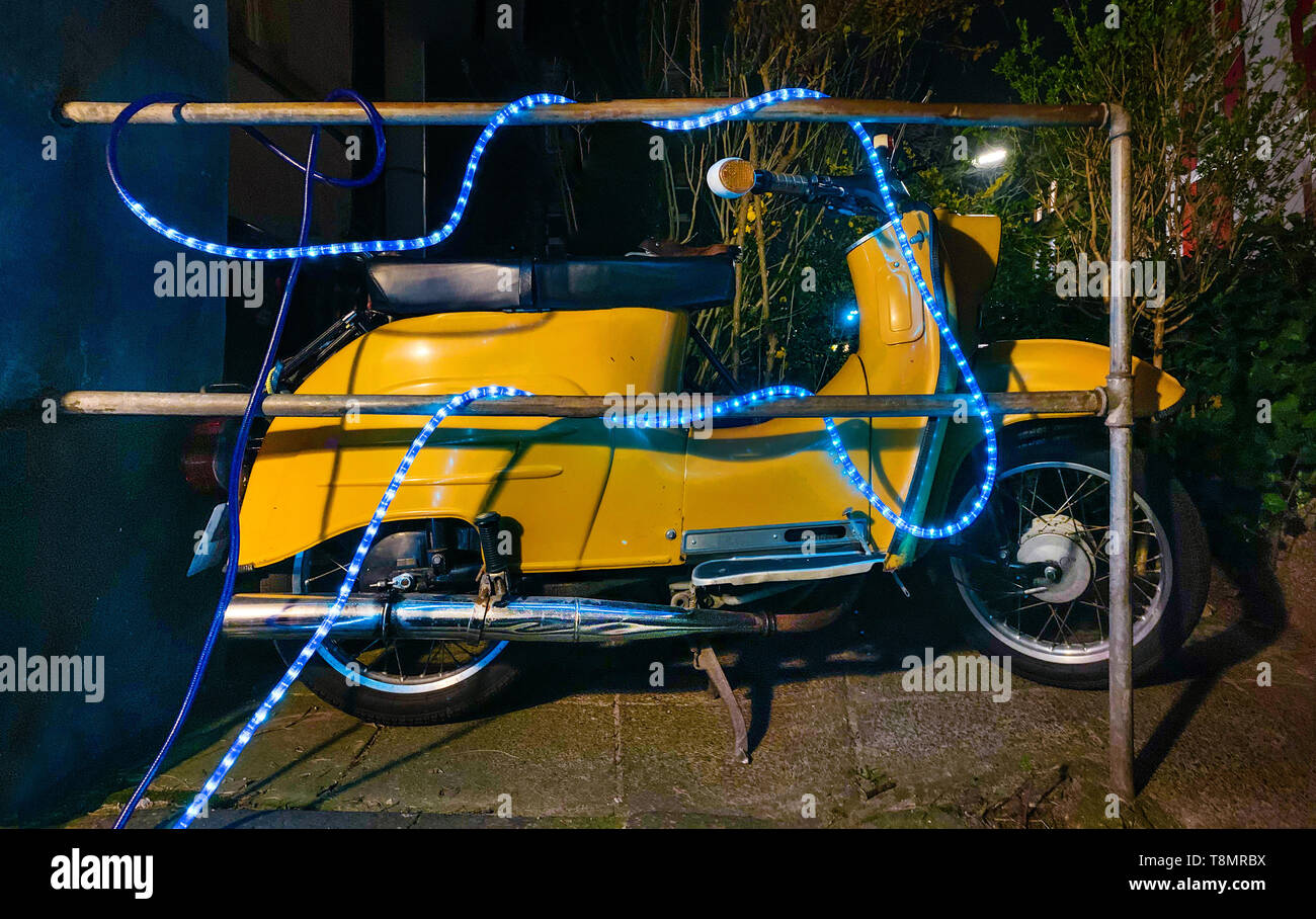 Lifestyle, a yellow scooter with a blue party light chain. Stock Photo