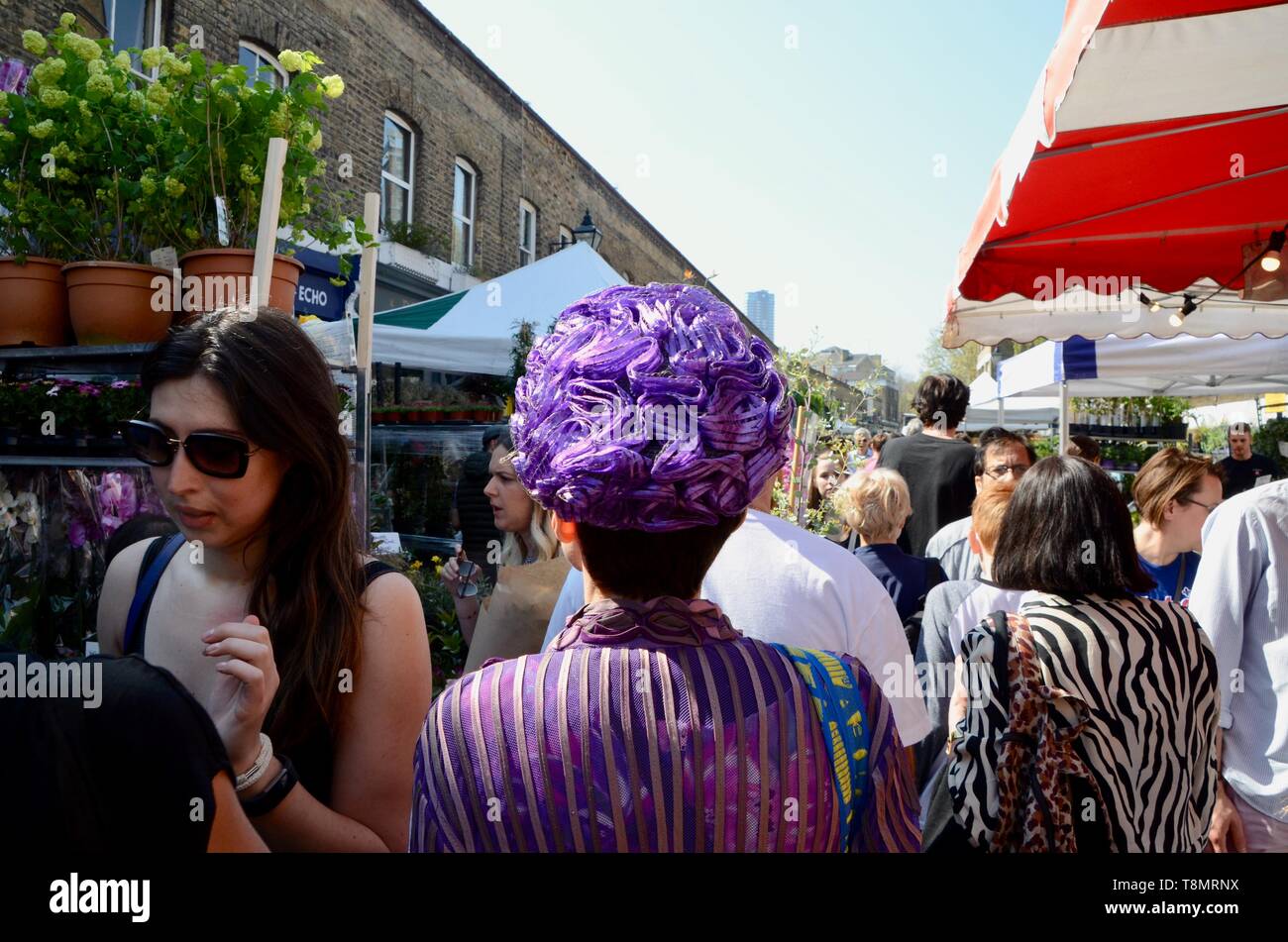 woman in exotic purple hat walks down columbia road flower market london england Stock Photo