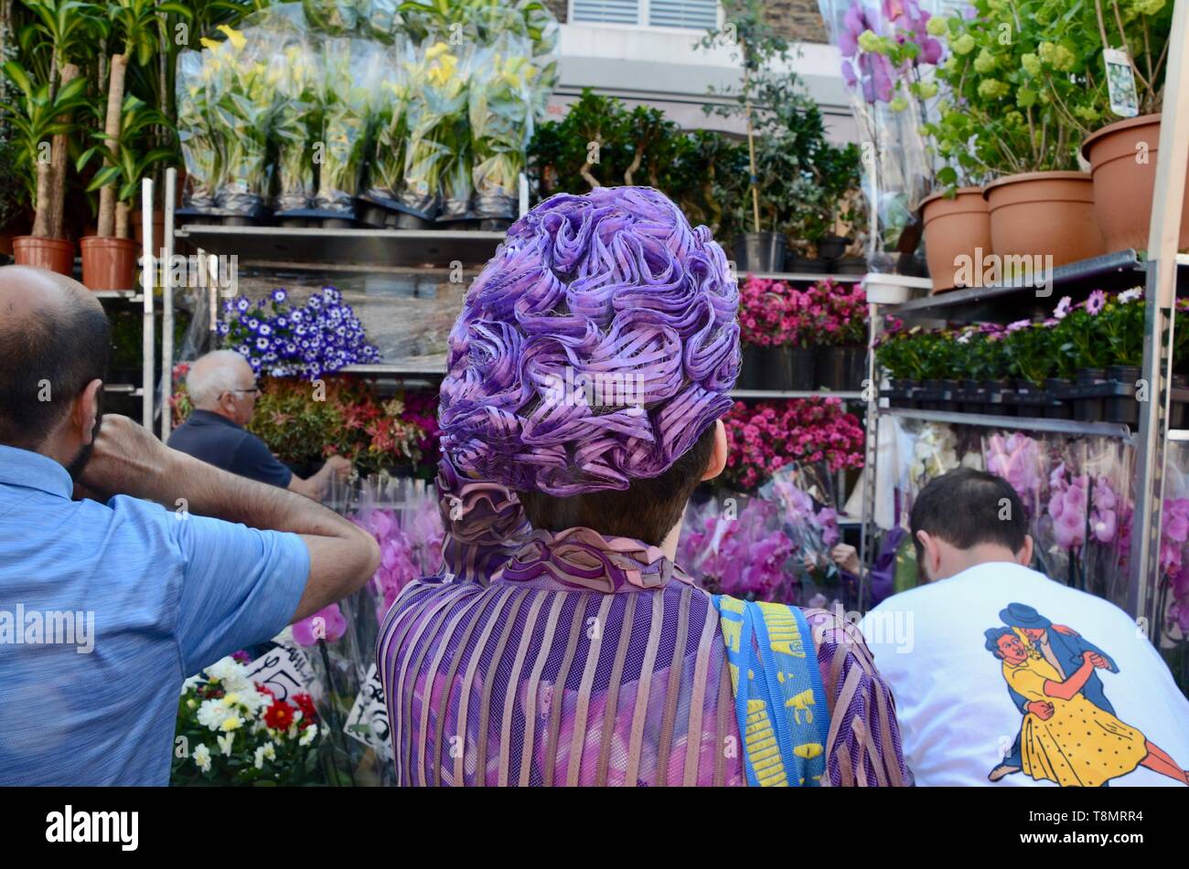 woman in exotic purple hat walks down columbia road flower market london england Stock Photo