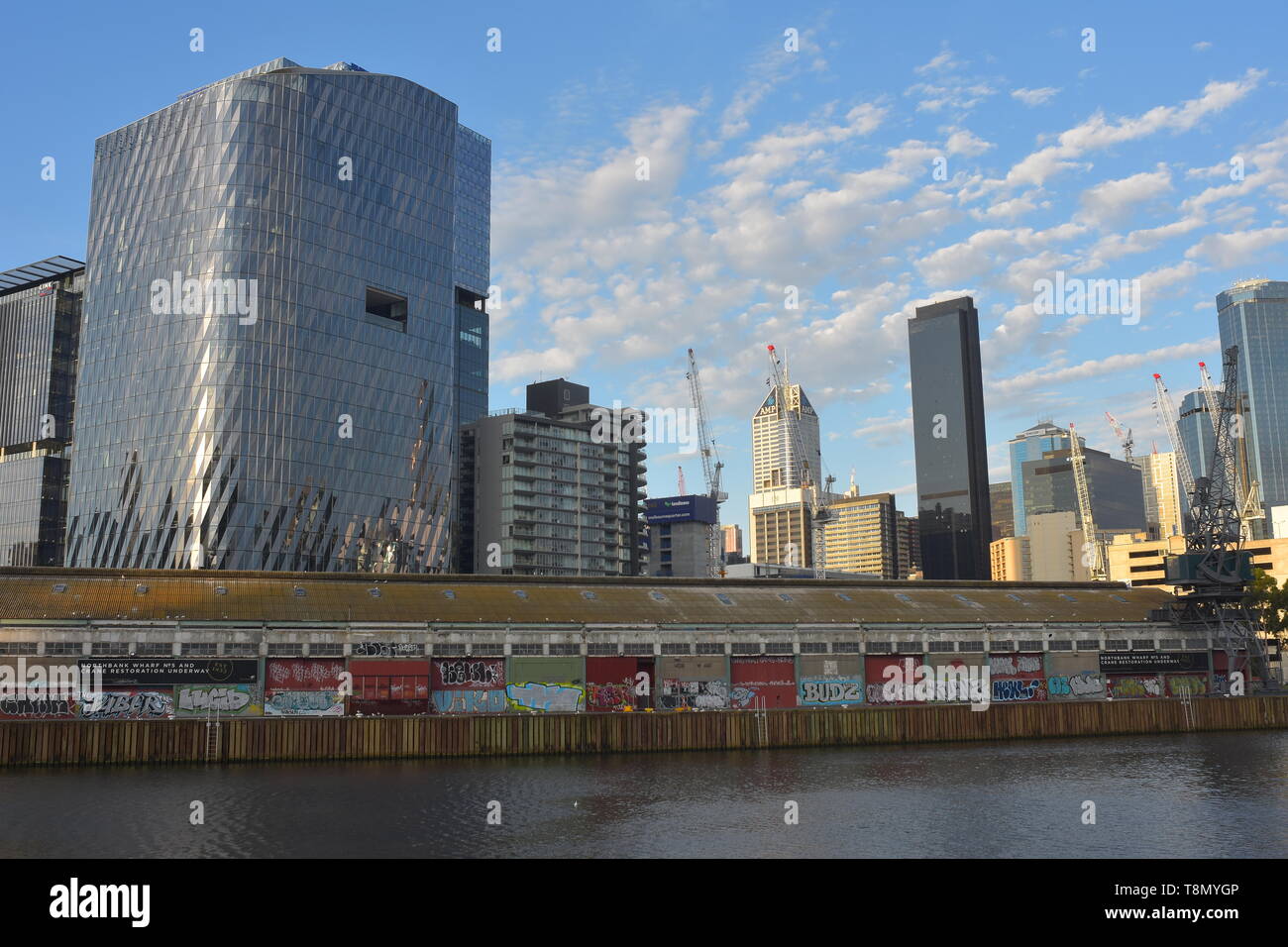 Industrial building with walls covered with graffiti on northern bank of Yarra River with modern high rise buildings in background. Stock Photo