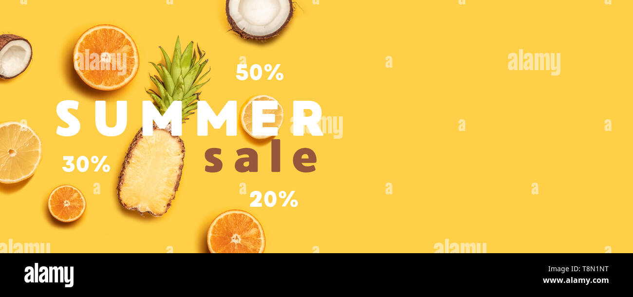 Pineapples, oranges, lemons, coconuts on yellow background. Summer fruits. Flat lay, top view, copy space Stock Photo