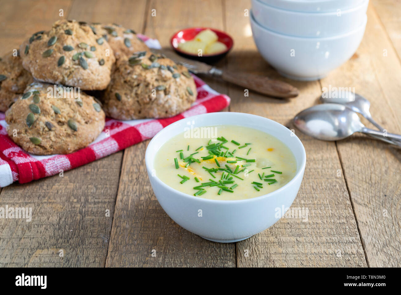 A bowl of smoked haddock, sweetcorn and potato chowder with a bread roll. Stock Photo
