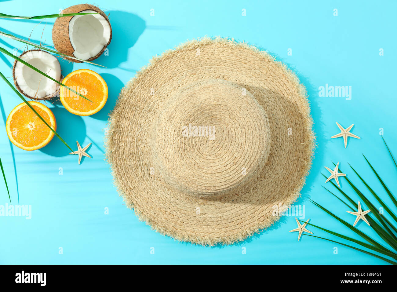Straw hat, oranges, coconuts, palm leaves and starfishes on color ...