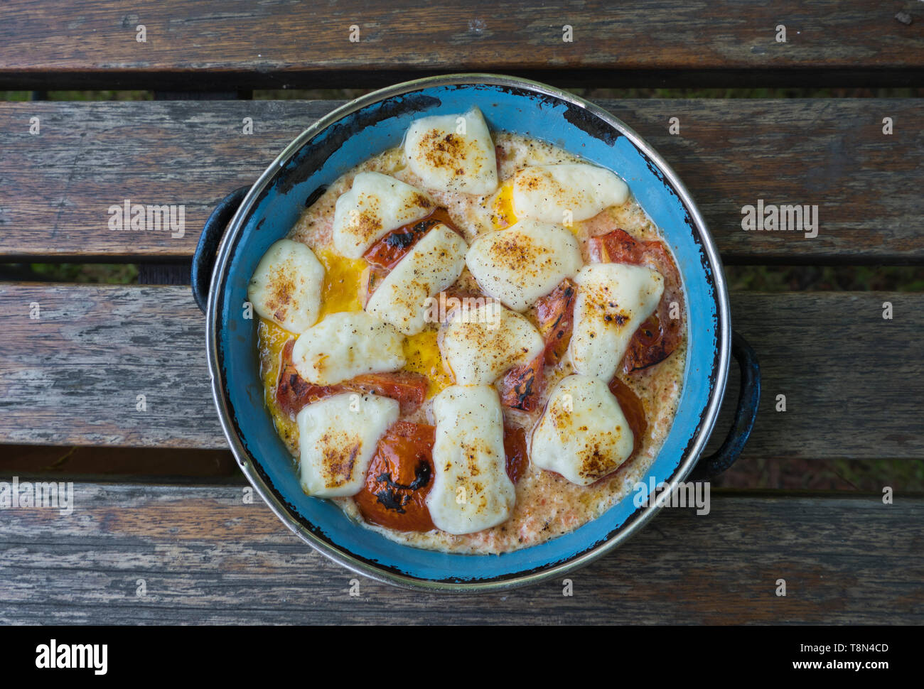 Still life of cooked eggs tomatoes and cheese in metal pan Stock Photo