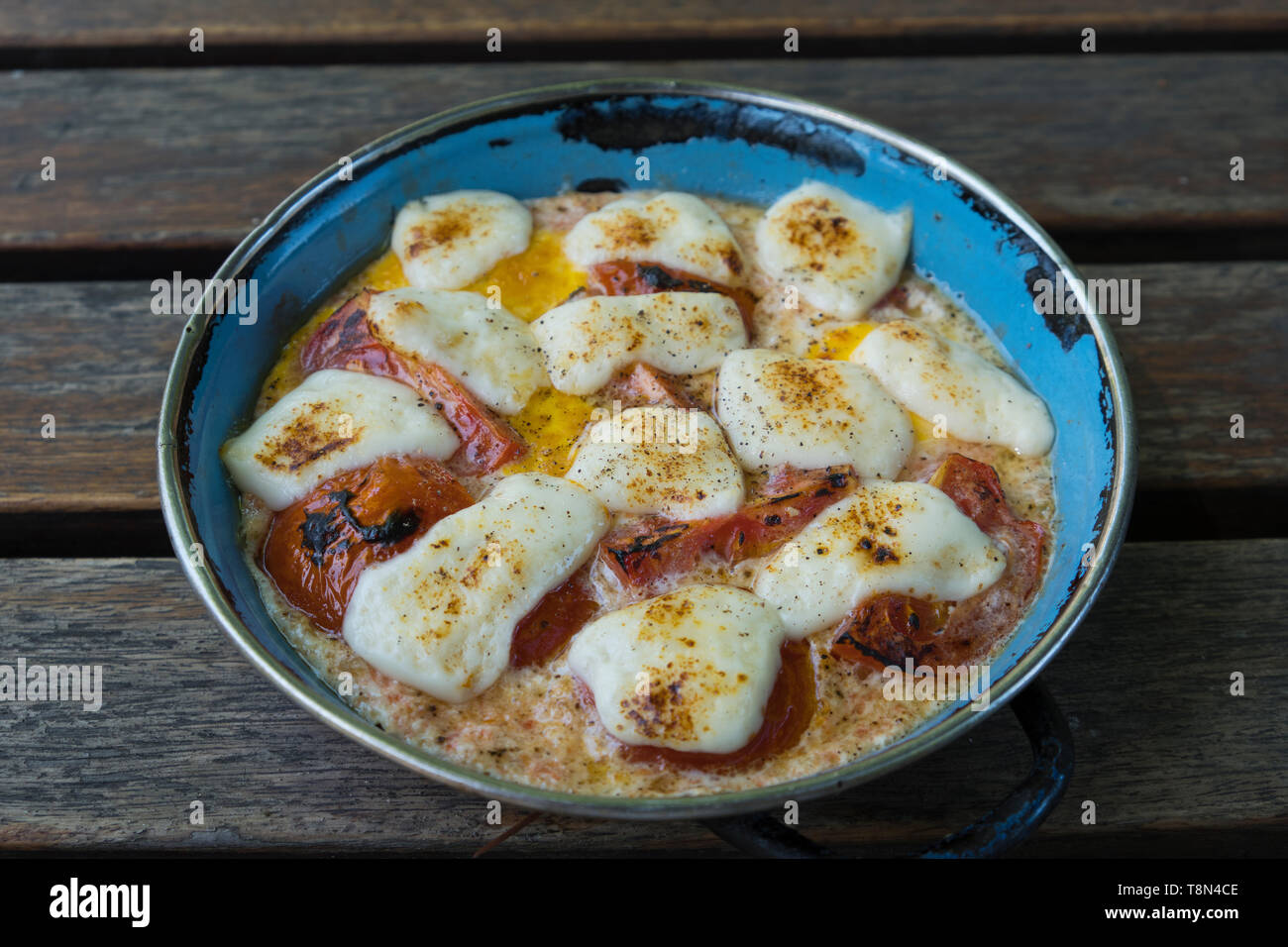 Still life of cooked eggs tomatoes and cheese in metal dish Stock Photo