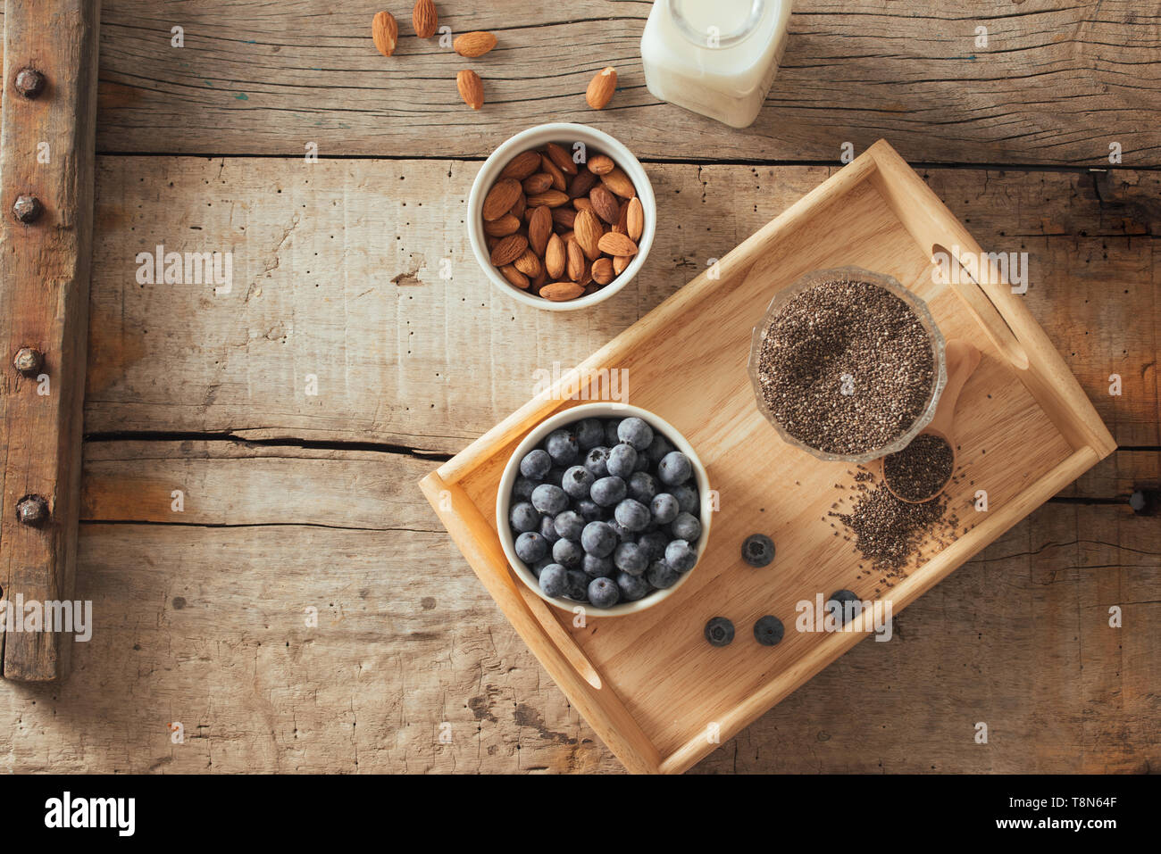 Fresh blueberries, almond and chia seeds with milk on wooden board. Ideal healthy breakfast concept. Stock Photo