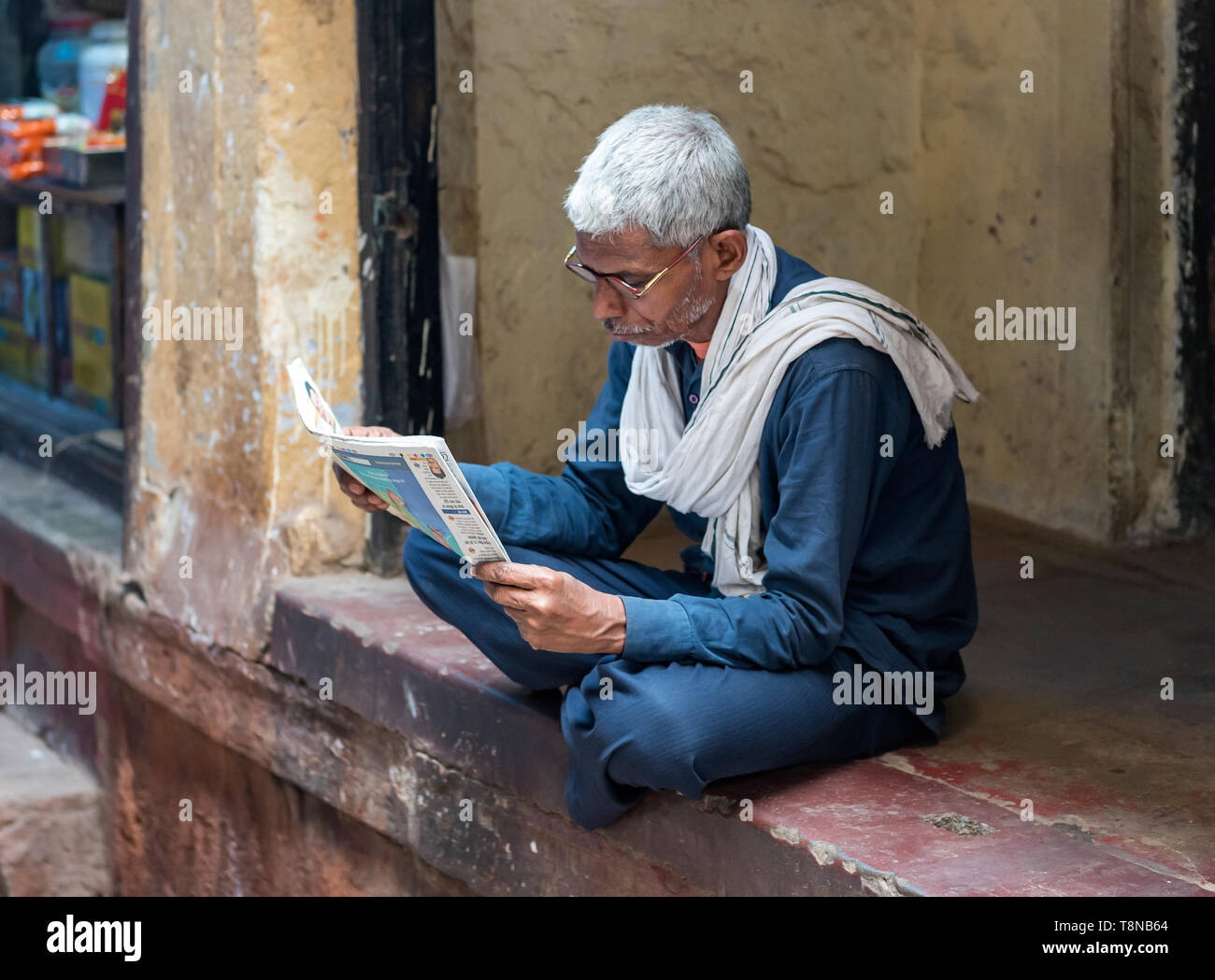 Man reads newspapers, Old City of Varanasi, India Stock Photo