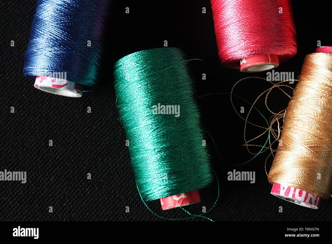 Blue, Green and Red Silk thread rolls on black background. These